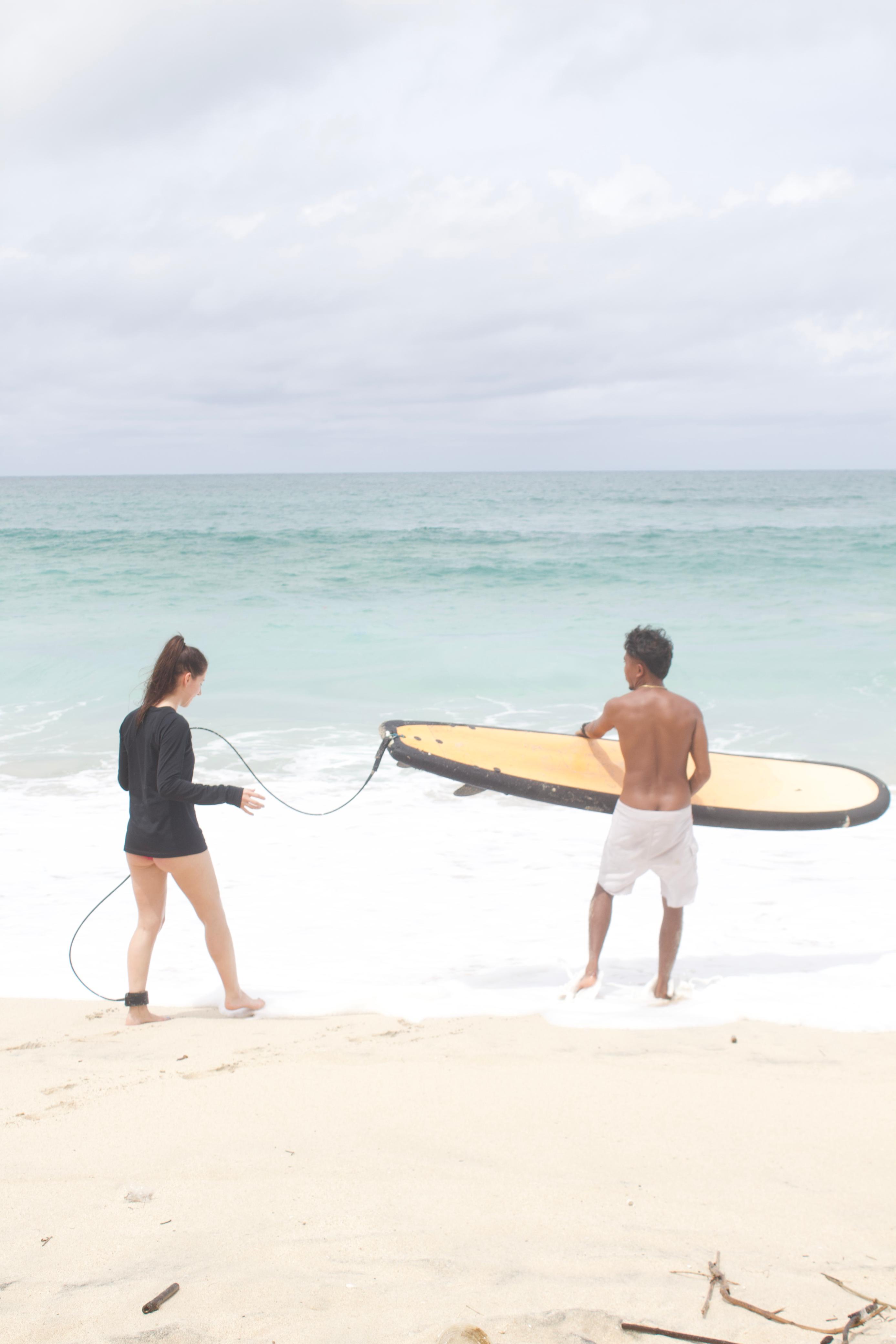 Surf instructor guiding student into the waves at Canggu Beach, Bali - Surf Lessons Canggu Professional surf instructor at Surf Lessons Canggu - Jl. Lkr. Nelayan No.442, Canggu, Bali - Contact +62 82230821314